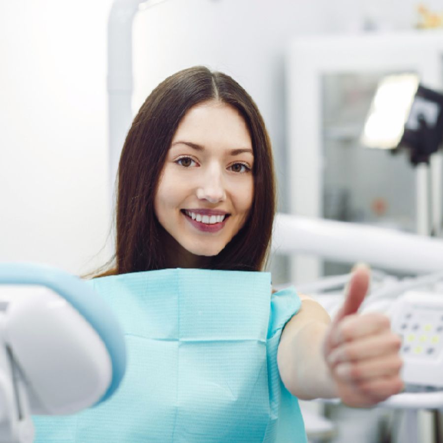 Woman showing thumbs up at a reception at the dentist