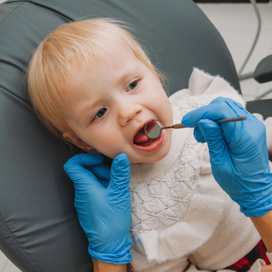The dentist examines the child's teeth in the dental chair.